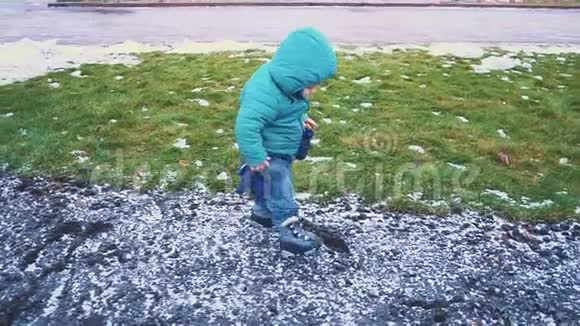 春天孩子沿着人行道跑草地融化的雪落在地上慢动作视频的预览图