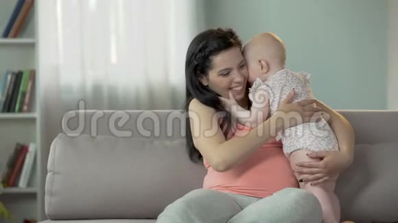 可爱的蹒跚学步的女孩亲吻和拥抱她的母亲温柔的家庭视频的预览图