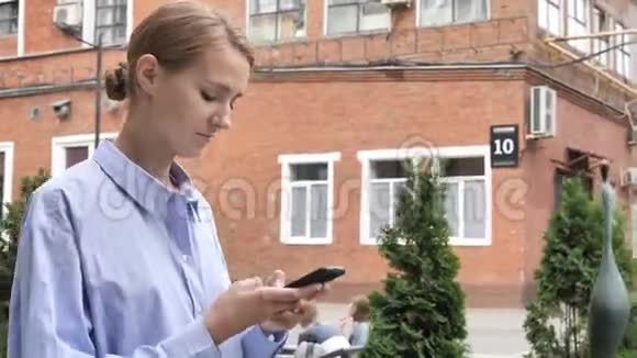 在街上忙着使用智能手机的步行妇女视频的预览图