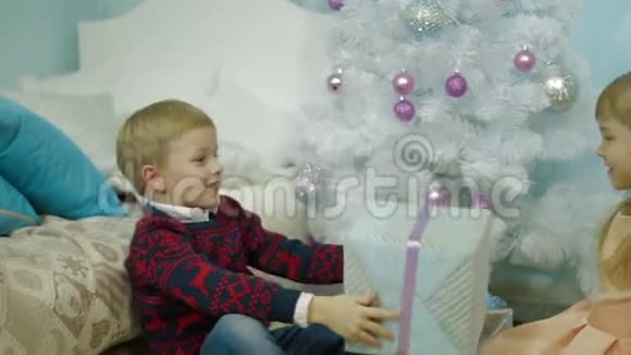 家中圣诞树旁圣诞礼物的快乐儿童视频的预览图