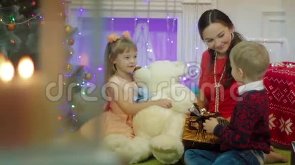 家中圣诞树旁的圣诞礼物祝母亲和孩子们快乐视频的预览图