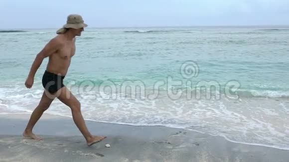 年轻的运动适合英俊的男人在海滩上快乐地跳跃制作轮子一些乐趣暑假的概念视频的预览图