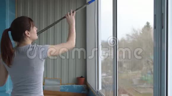 年轻女子用橡皮拖把擦窗户视频的预览图