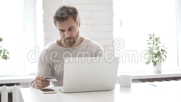 手提电脑上帅哥用银行卡在线购物视频的预览图