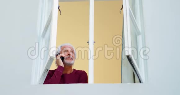 老人在家靠窗户打手机视频的预览图