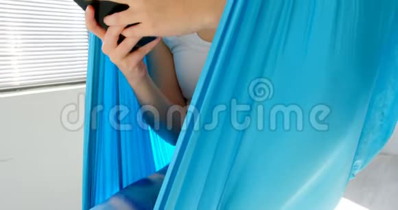 女人在吊床上荡秋千时使用手机视频的预览图