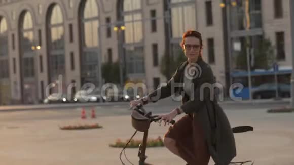 年轻女子骑着自行车在晚市看着镜头视频的预览图