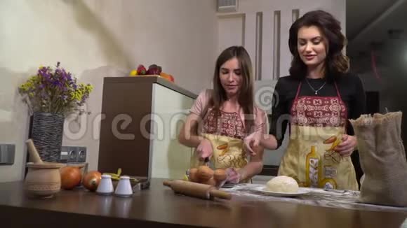 两个黑发女人在厨房做饭一个切土豆另一个撒面团有点慢动作视频的预览图