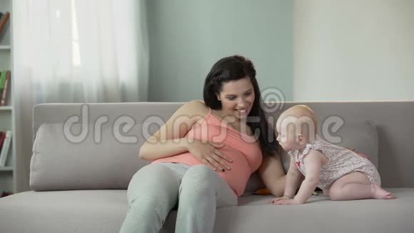 美丽的孕妇轻轻地抚摸着腹部与可爱的婴儿一起享受时光视频的预览图