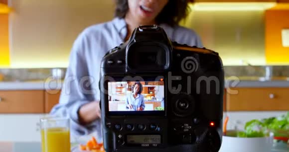 女博主在厨房切胡萝卜的同时录制视频视频的预览图