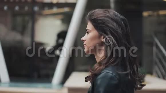穿着皮夹克的漂亮年轻女人正走在商务中心附近那个女孩把她的头发梳得到处都是视频的预览图
