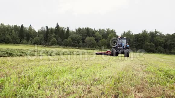 农业拖拉机在森林附近的农场割草视频的预览图