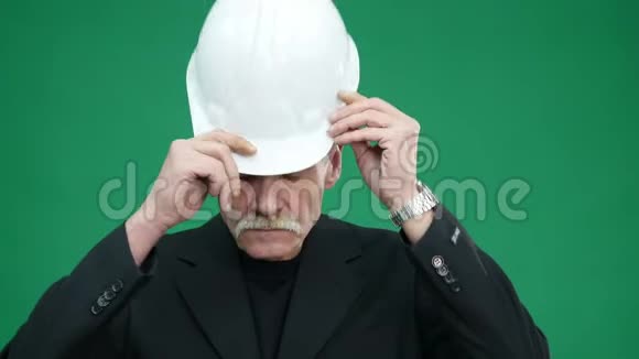 穿着西装戴着头盔的老高级商务男士幸福微笑的画像被绿油油的背景隔绝了人类的情感视频的预览图