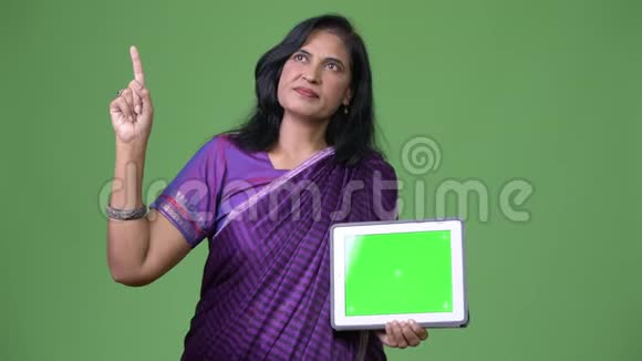 成熟美丽的印度女人一边思考一边显示数字平板电脑一边指指点点视频的预览图