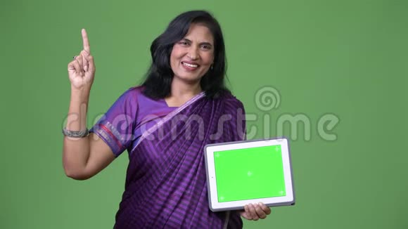 成熟快乐美丽的印度女人展示数字平板电脑手指视频的预览图