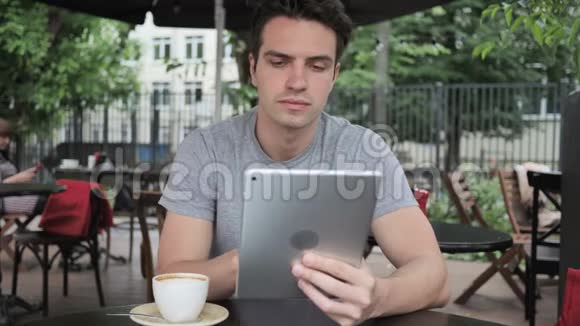 坐在咖啡馆露台上的男人在平板电脑上在线视频聊天视频的预览图