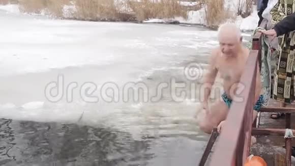 一个年迈的白发男子跳进冰洞的冰水里冰水硬化视频的预览图