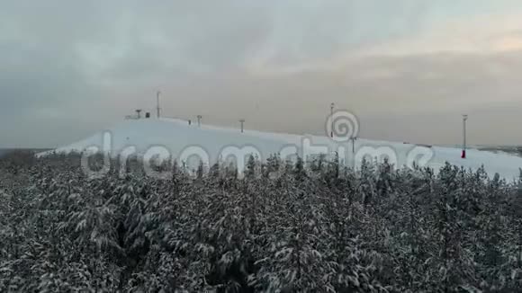 照相机飞过森林朝滑雪场飞去在滑雪小屋的冬季空中观景台滑雪场的顶部泰山视频的预览图