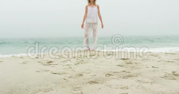 在海滩上做瑜伽的高加索女人的正面景色视频的预览图