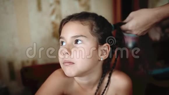 妈妈在小女儿头上做辫子理发师在给年轻女孩编辫子准备好准备视频的预览图