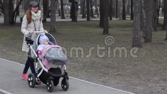 家庭母性和人的概念幸福的母亲和婴儿睡在春天公园散步的婴儿车里视频的预览图
