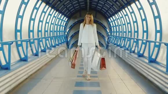 Steadicam射击时尚的年轻女性带着购物袋谈论现代玻璃过渡或隧道视频的预览图
