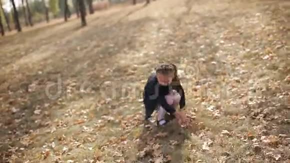有雀斑的年轻母女正在公园里和落叶的黄叶嬉戏视频的预览图