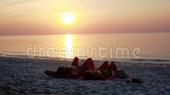 日落时一对情侣在热带海滩上浪漫地躺在阳光下1920x1080视频的预览图