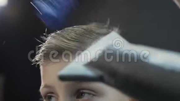 理发师用吹风机和梳子给男孩做发型理发店可爱的孩子新发型视频的预览图