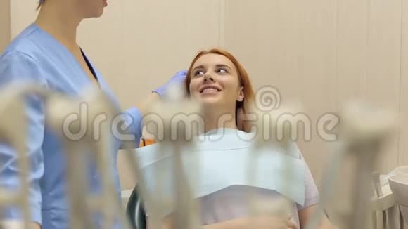 年轻漂亮的女孩在牙科办公室和她的牙医交谈牙医视频的预览图