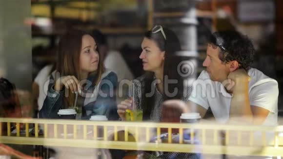 三个快乐的朋友在鸡尾酒咖啡厅的餐桌上喝酒和玩得开心一人两美视频的预览图