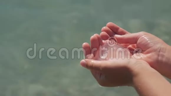 夏天小白种人的孩子手里拿着透明的水母在室外海水中视频的预览图