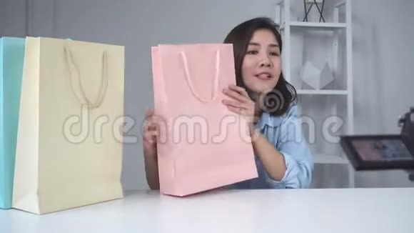 快乐美丽的亚洲女人从品牌或她的订户手中取出礼物女博主从相机录制视频视频的预览图