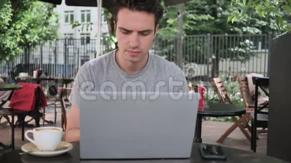 损失男人坐在咖啡馆露台上对笔记本电脑的成绩感到沮丧视频的预览图