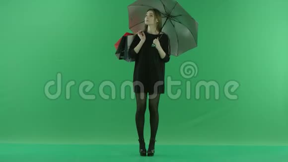 美丽的适合年轻女子在伞下购物后彩色钥匙绿色背景视频的预览图