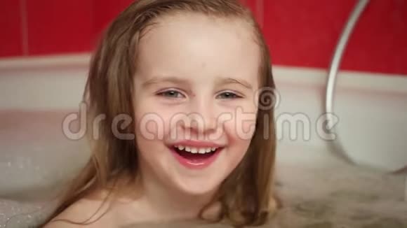 可爱的小女孩用泡沫洗澡视频的预览图