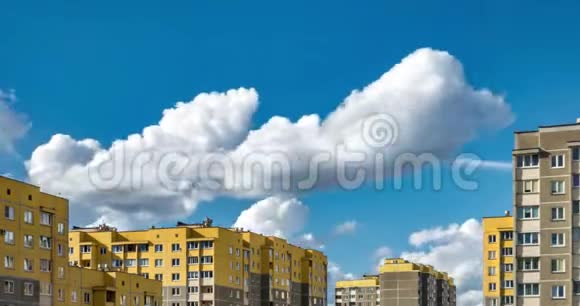 黄色多层公寓楼背景下白色蓬松滚动云的时间间隔剪辑视频的预览图