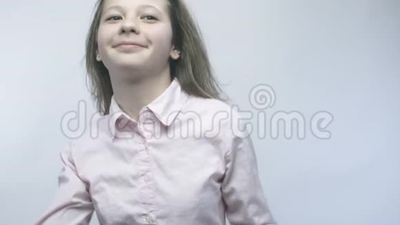 一个年轻的女孩穿着一件白色的衬衫在白色的背景上跳舞她的头发穿着慢条斯理的视频的预览图