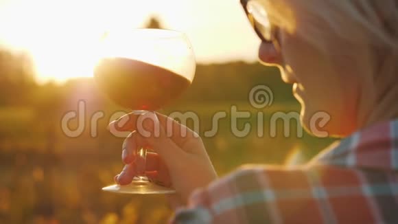 一个女人看着一杯红酒在阳光下品酒和旅游概念视频的预览图