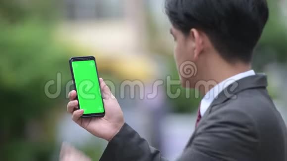 年轻英俊的亚洲商人在户外街头展示电话视频的预览图
