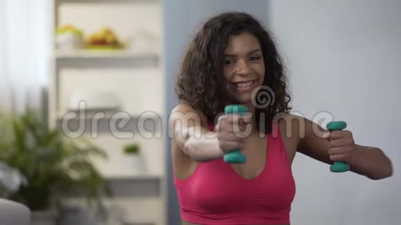 混合种族的女人在家里用哑铃工作健康的生活方式健身视频的预览图