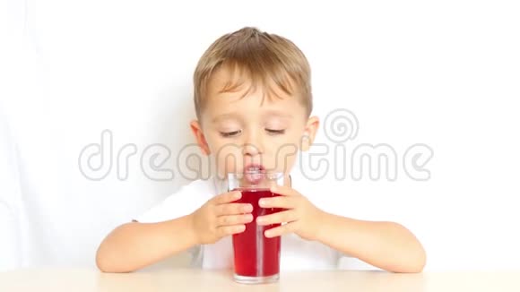 一个孩子在白色的背景上从玻璃烧杯中喝果汁然后他微笑视频的预览图