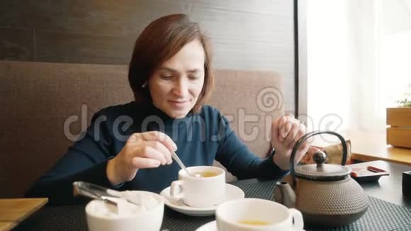 咖啡馆里的一个女孩在一杯茶里搅拌糖一个女人正在咖啡馆里喝绿茶视频的预览图