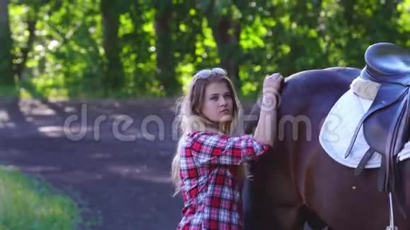 年轻的金发女人穿着格子衬衫和他的马一起散步女人与马交流视频的预览图