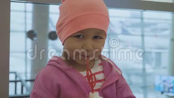一个小孩在机场喝果汁和看镜头的肖像视频的预览图