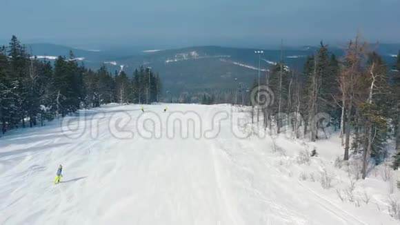 滑雪坡上人们开始在针叶树和缆车附近的跑道上滑雪的美丽鸟瞰图视频的预览图