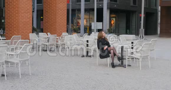 年轻女子坐在户外咖啡馆里视频的预览图