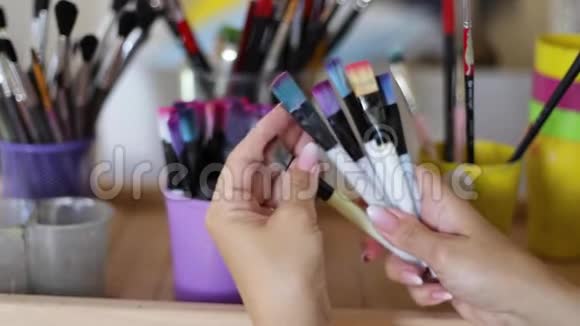 女人选择画笔作画艺术观念画室里有很多刷子用刷子把手收起来视频的预览图