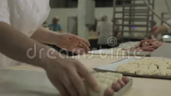 在面包店里一个女人把香肠包在生的膨化糕点里女人面包师用生热狗卷面团视频的预览图