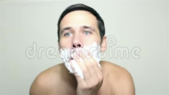 年轻的帅哥用剃须泡沫视频的预览图